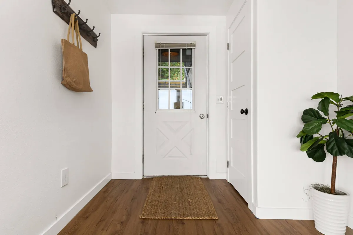 A view of the inviting front door area, featuring a plant, cozy rug, and coat hook—an ideal spot for returning from walks or hanging up leashes after a day outside. The space feels warm and welcoming, suggesting a transition from outdoor adventure to indoor comfort.