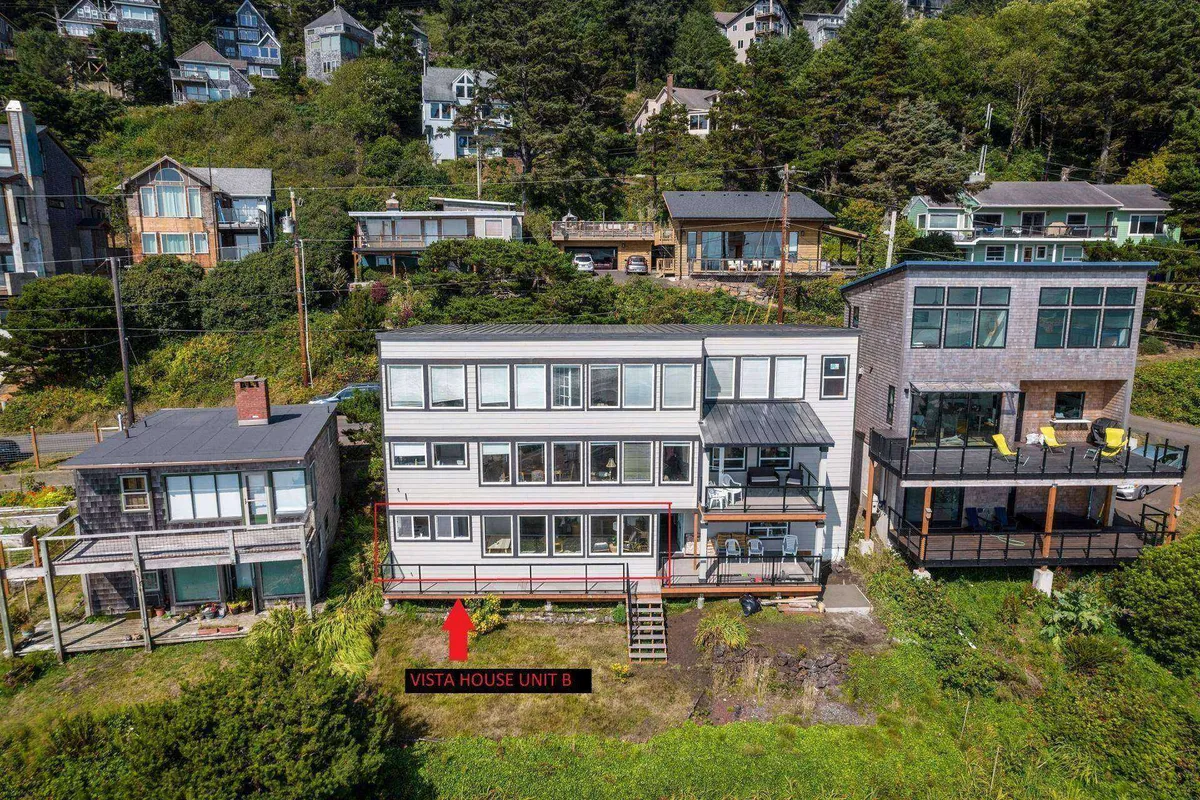 This image spotlights Vista House Unit B with its inviting porch, surrounded by other coastal homes and the beautiful natural landscape. The scene conveys a sense of community and relaxation, with hints of sunset light and comfortable outdoor spaces for unwinding after a day of adventure.