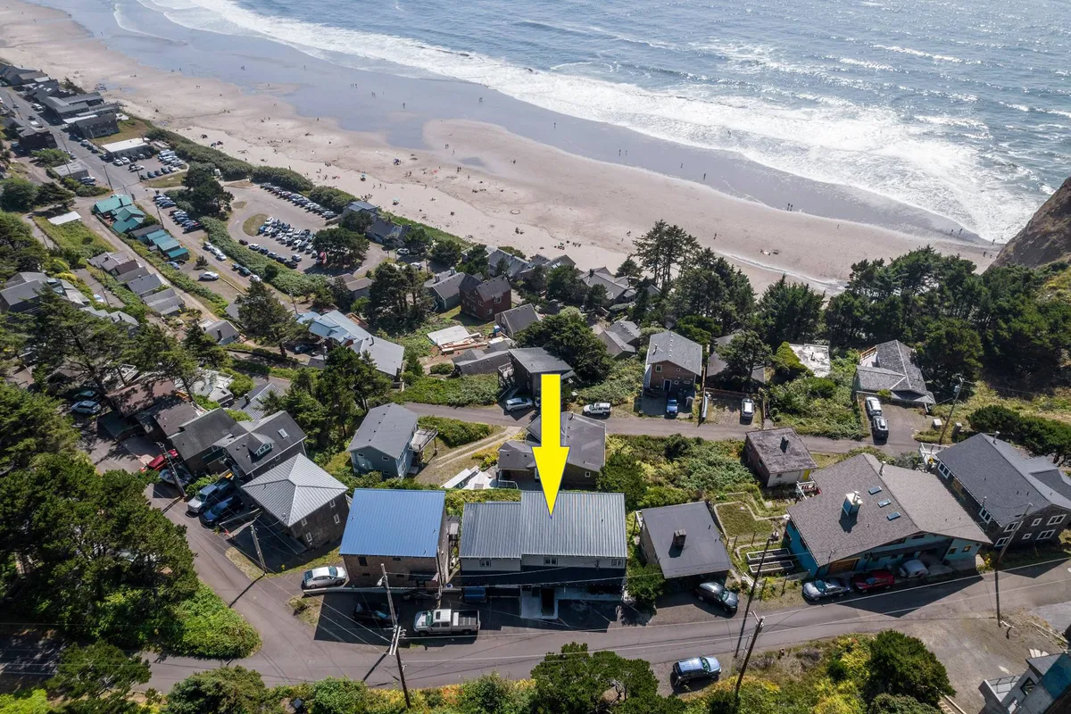 An exterior perspective highlighting the beach, ocean, and the inviting neighborhood, including the property itself. People can be seen engaging in beach activities, and the scene radiates a relaxed, community-oriented vibe.